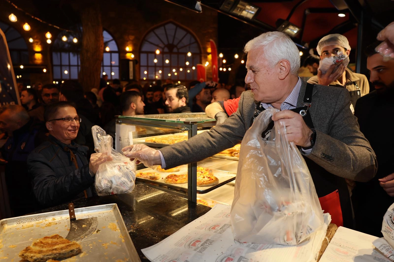 Bursa Büyükşehir Belediye Başkanı Mustafa Bozbey, Ramazan ayında Abdal Meydanı'nda düzenlenen sahur etkinliğinde vatandaşlara tahanlı pide ikram ediyor.
