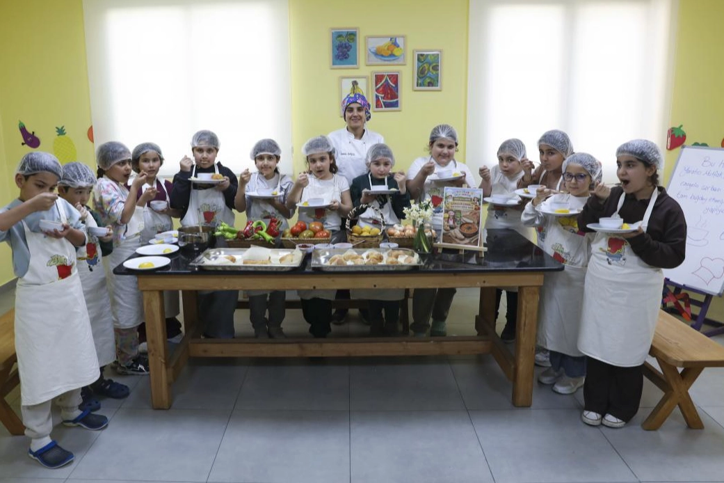 Mersin'de bir çocuk mutfak atölyesinde yemek yaparken gülümsüyor