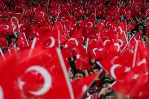 Türkiye ve Romanya milli takımlarının futbolcuları sahada mücadele ederken, Türkiye Futbol Federasyonu'nun stadyuma erken gelinmesi yönündeki uyarısını gösteren görsel.