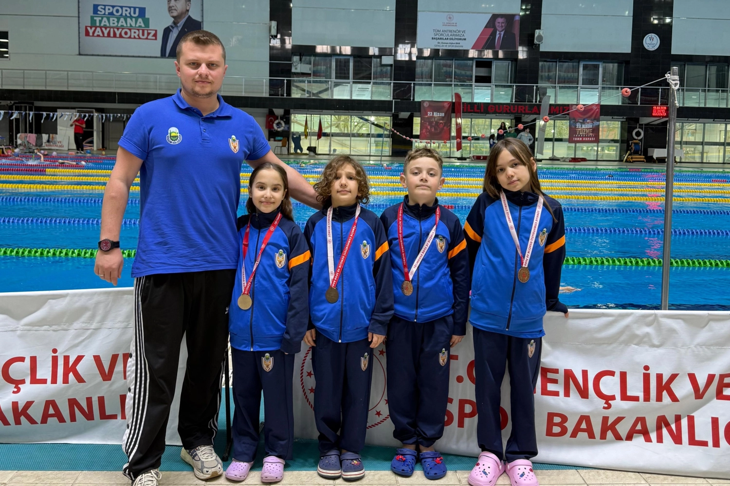 İnegöl Belediyespor yüzme takımı sporcuları madalyalarıyla birlikte gururla poz veriyor.