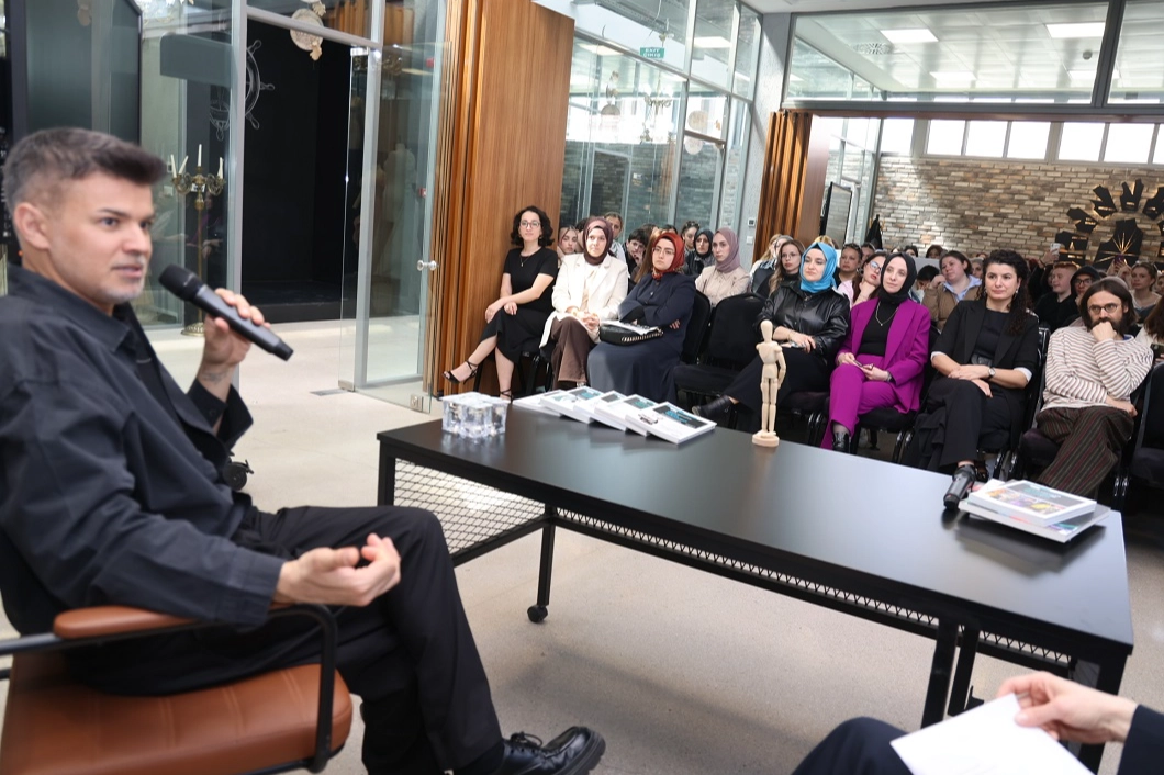 Moda tasarımcısı Cihan Nacar, Kocaeli Moda Akademisi'nde öğrencilere moda tasarımı ve kariyer hakkında ipuçları verirken.