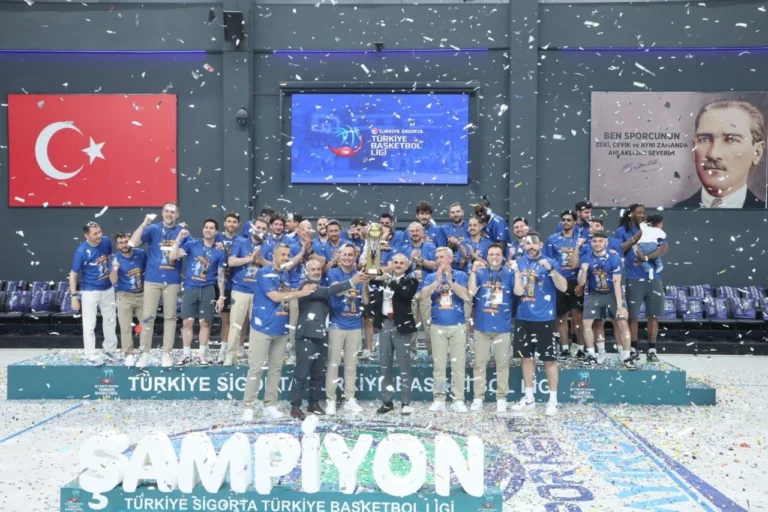 Çayırova Belediyesi Basketbol Takımı oyuncuları ve teknik heyeti, şampiyonluk kupasıyla zafer pozu veriyor.