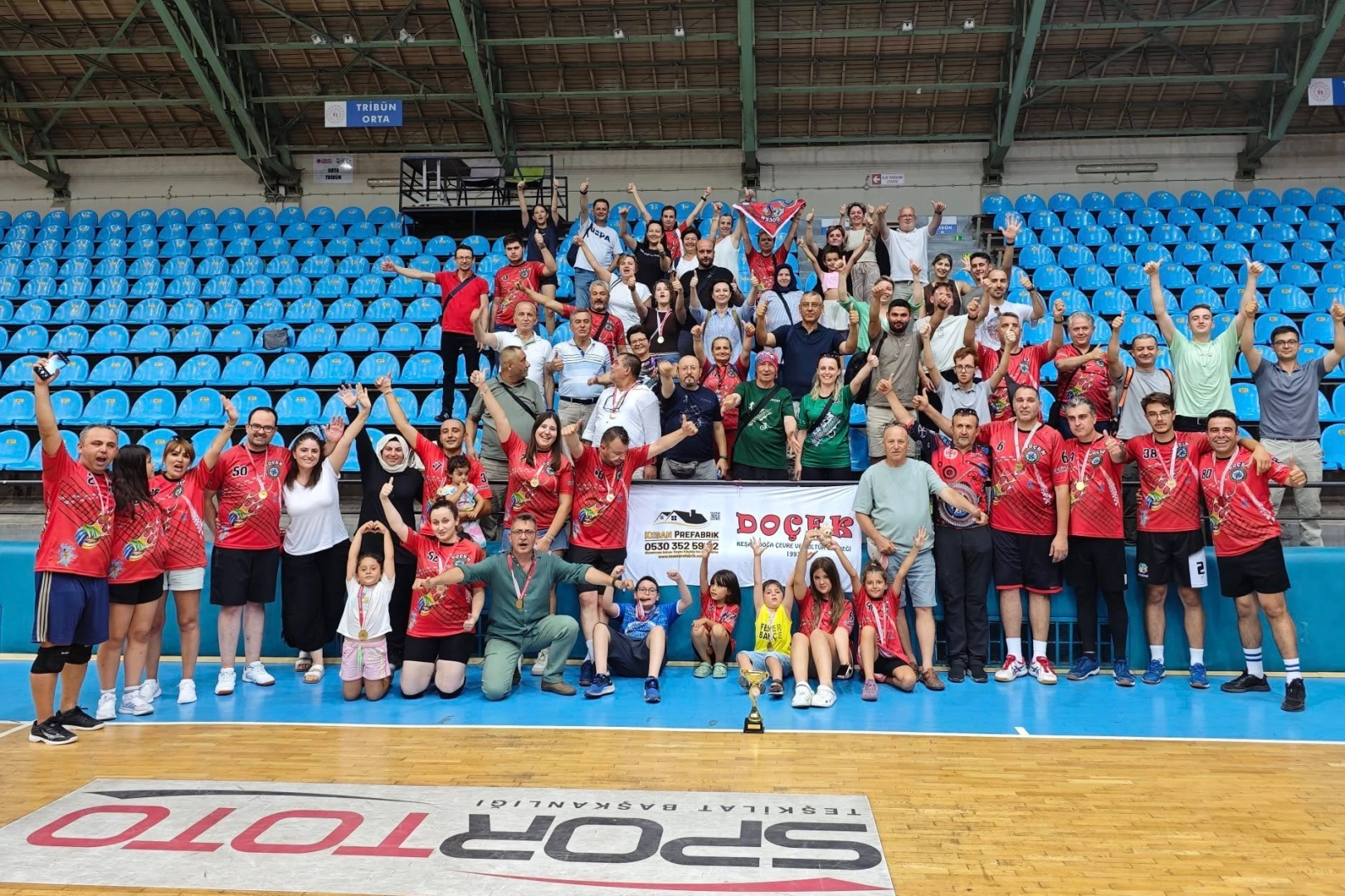 DOÇEK Voleybol Takımı oyuncuları kupayla zafer pozu verirken